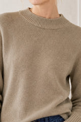 Model wearing the Aspiga Merino Wool Crew Neck Jumper in Oatmeal with dark denim jeans, full-length front view