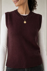 Close-up of a model wearing the Aspiga Merino Wool Knitted Short Tank in Burgundy with a gold pendant necklace
