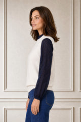 Model wearing the Aspiga Merino Wool Knitted Short Tank in Ivory over a navy lace blouse with jeans, smiling, hands in pockets