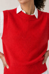 Model wearing the Aspiga Merino Wool Knitted Short Tank in Red, a ribbed knit crew-neck sweater vest layered over a white collared blouse, alternate view