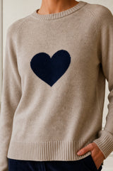 Close-up of a model wearing the Aspiga Cashmere Crew Neck Heart Jumper in Oat/Navy, showing the contrast heart knit motif