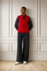Model wearing the Aspiga Merino Wool Zip Through Gilet in Red over a navy top with black trousers, full-length front view, hands in pockets