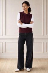 Model wearing the Aspiga Merino Wool Knitted Short Tank in Burgundy over a white top with a black skirt, arms crossed