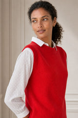 Model wearing the Aspiga Merino Wool Knitted Short Tank in Red, a ribbed knit crew-neck sweater vest layered over a white collared blouse, alternate view