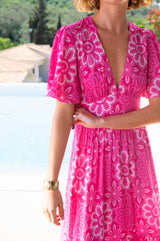 Woman wearing a pink floral dress with a blurred outdoor background