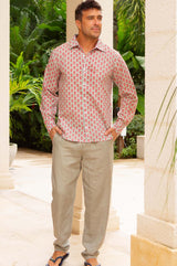 A model wearing a long-sleeved, pink and khaki geometric patterned cotton shirt with a classic collar paired with neutral linen trousers
