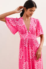 Woman wearing a pink floral dress with her arm elevated to display the floaty short sleeve