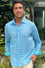 A man wearing a hyacinth blue to turquoise colored geometric patterned organic cotton shirt with a collar.