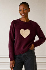 Model wearing the Aspiga Cashmere Crew Neck Heart Jumper in Burgundy/Oat, a crew-neck jumper with a contrast heart motif, front view