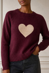 Close-up of a model wearing the Aspiga Cashmere Crew Neck Heart Jumper in Burgundy/Oat, showing the contrast heart knit motif