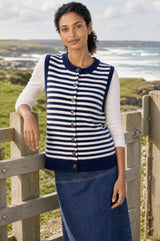Lifestyle photo of a model wearing the Aspiga Merino Wool Stripe Button Knit Gilet in Navy/Off White, a breton-striped button-front knit gilet