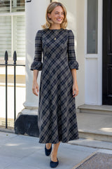Model wearing the Aspiga Elizabeth Check Dress in Blue/Grey with a gold necklace, full-length front view walking outdoors