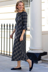 Model wearing the Aspiga Elizabeth Check Dress in Blue/Grey with navy ballet flats, full-length side view walking, smiling
