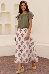 Woman wearing a white midi skirt with a pink and green floral block print pattern, paired with a olive green top and beige espadrille wedges.