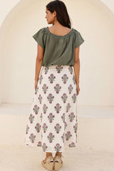 Back view of a woman wearing a white midi skirt with a pink and green floral block print pattern, paired with a green top and beige espadrille wedges.