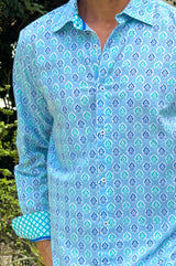 A man wearing a hyacinth blue to turquoise colored geometric patterned organic cotton shirt zoomed in on the collar
