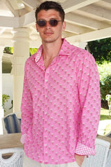A man wearing sunglasses and a periwinkle pink/rust colored long-sleeved cotton shirt with a classic collar.