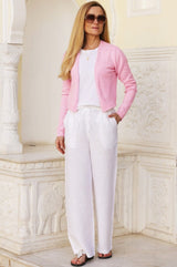 Lucy in the edge to edge pink merino wool cardigan with a v neckline styled with white linen trousers