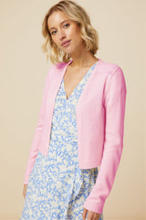 The edge to edge pink merino wool cardigan with a v neckline styled over a blue floral summer dress