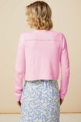 The edge to edge pink merino wool cardigan with a v neckline styled over a blue floral summer dress