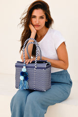 The wide leg linen trousers in blue grey with an elasticated waistband styled with Victoria trainers and a white t-shirt and Aspiga Bombon mini tote bag sitting down