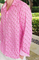 A zoom in of  man wearing sunglasses and a periwinkle pink/rust colored long-sleeved cotton shirt with a classic collar and contrast cuffs rolled up