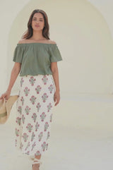 Video of a woman wearing a white midi skirt with a pink and green floral block print pattern, paired with a green top and beige espadrille wedges.