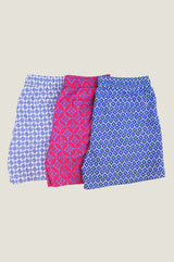 Three pairs of patterned swim shorts in blue and white, pink and blue, and blue and green, displayed side by side on a white background.
