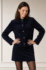 Model wearing the Aspiga Corduroy Collared Jacket in Deep Navy over a matching corduroy mini skirt, hands on hips, front view