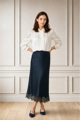 Model wearing the Aspiga Satin Jacquard Spot Slip Skirt in Navy with a cream blouse, full-length front view, hands on hips