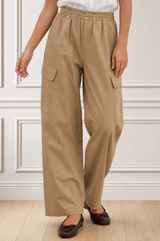 Close-up crop of a model wearing the Aspiga Matcha Trousers in Camel, showing the elasticated waist and cargo pockets