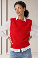 Model wearing the Aspiga Merino Wool Knitted Short Tank in Red, a ribbed knit crew-neck sweater vest layered over a white collared blouse, front view