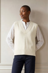 Model wearing the Aspiga Merino Wool V Neck Tank in Ivory, a fine-knit v-neck tank layered over a blouse, front view