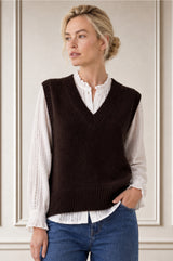 Model wearing the Aspiga Merino Wool V Neck Tank in Chocolate, a fine-knit v-neck tank layered over a blouse, front view