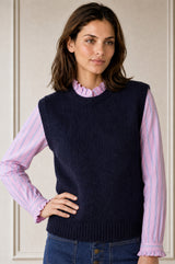 Model wearing the Aspiga Alpaca Blend Knitted Short Tank in Navy, a ribbed knit sweater vest layered over a striped blouse, front view
