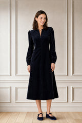 Model wearing the Aspiga Stretch Corduroy Zip Front Dress in Deep Navy, full-length front view, smiling