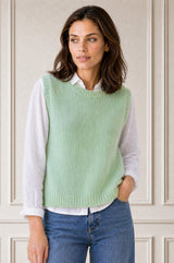 Model wearing the Aspiga Alpaca Blend Knitted Short Tank in Light Sage, a ribbed knit sweater vest layered over a white blouse, front view