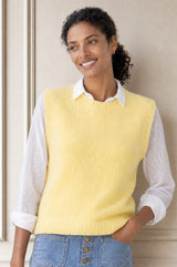 Model wearing the Aspiga Alpaca Blend Knitted Short Tank in Pale Yellow, a ribbed knit sweater vest layered over a white blouse, front view