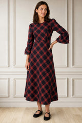 Model wearing the Aspiga Elizabeth Check Dress in Red/Blue with black Mary Jane shoes, full-length front view, hand on hip