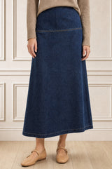 Model wearing the Aspiga Dropped Waist Denim Skirt in Indigo with a tan jumper, cropped front view