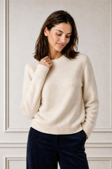 Model wearing the Aspiga Merino Wool Crew Neck Jumper in Ivory with navy corduroy trousers, hand near collar
