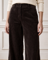 Close-up crop of a model wearing the Aspiga Wide Leg Chunky Corduroy Trouser in Chocolate Brown with a cream jumper, front view