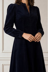 Close-up of the zip-front neckline of the Aspiga Stretch Corduroy Zip Front Dress in Deep Navy, hands clasped