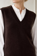 Model wearing the Aspiga Merino Wool V Neck Tank in Chocolate, a fine-knit v-neck tank layered over a blouse, alternate view