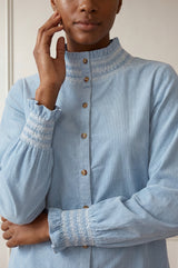 Close-up of the smocked embroidered collar and cuff detail of the Aspiga Embroidered Smocked Baby Cord Blouse in Ice Blue