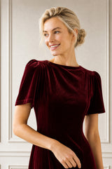 Close-up of a model wearing the Aspiga Velvet Scoop Back Dress in Wine Red, showing the sleeve and shoulder detail