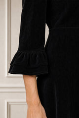Close-up of the tiered ruffle cuff detail of the Aspiga Elizabeth Stretch Corduroy Midi Dress in Black