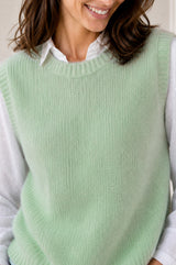 Model wearing the Aspiga Alpaca Blend Knitted Short Tank in Light Sage, a ribbed knit sweater vest layered over a white blouse, alternate view