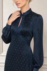 Close-up of the keyhole neckline of the Aspiga Satin Jacquard Spot Dress in Navy, hand at collar