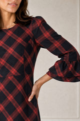 Close-up of a model wearing the Aspiga Elizabeth Check Dress in Red/Blue, showing the tiered ruffle cuff detail, hand on hip